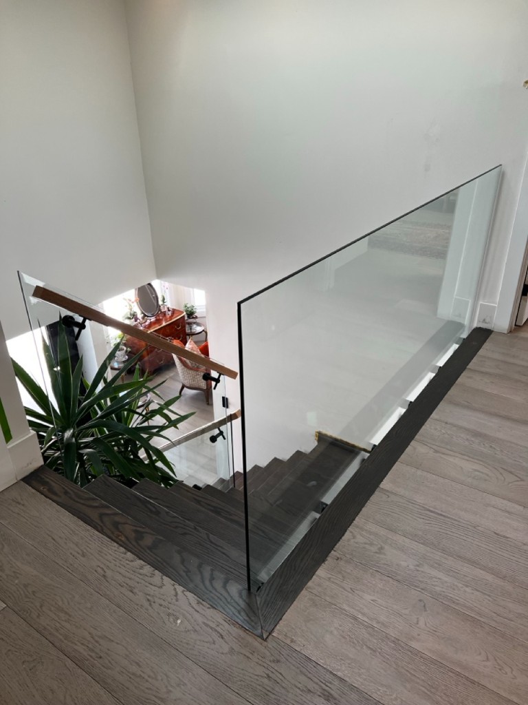Stair-landing glass guardrail overlooking an open-plan home