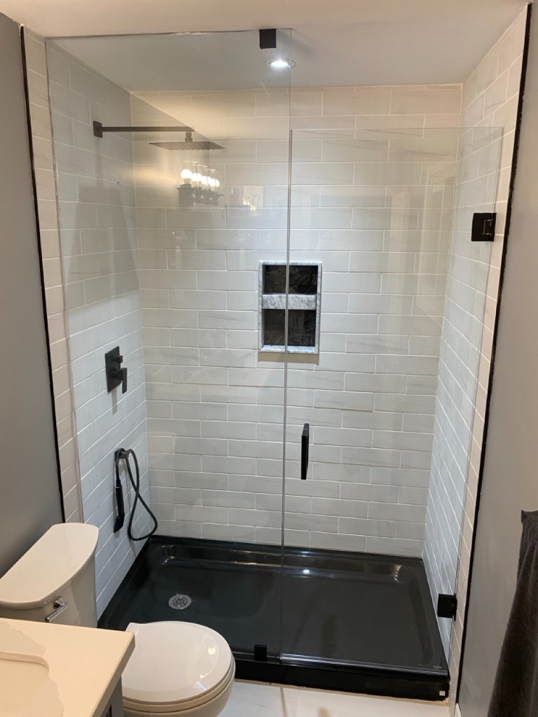 Completed frameless shower enclosure with white subway tile