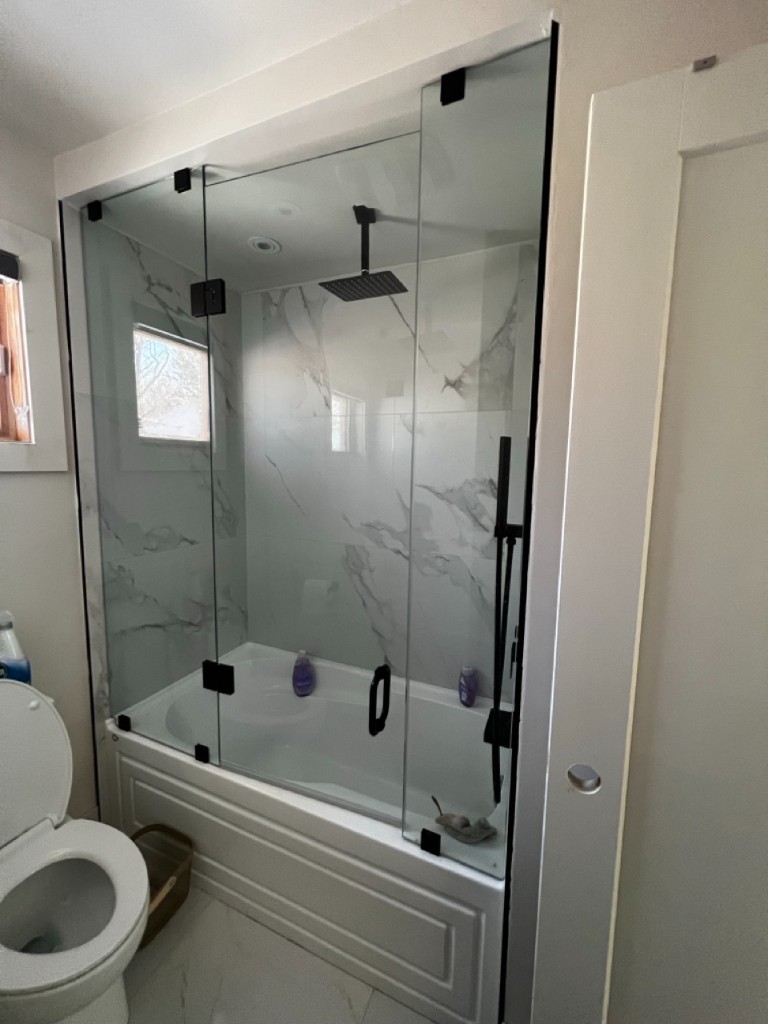 Marble shower with frameless glass and matte-black fixtures